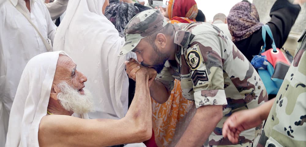 رجل أمن يقبل يد حاج مسن في لفتة طيبة.