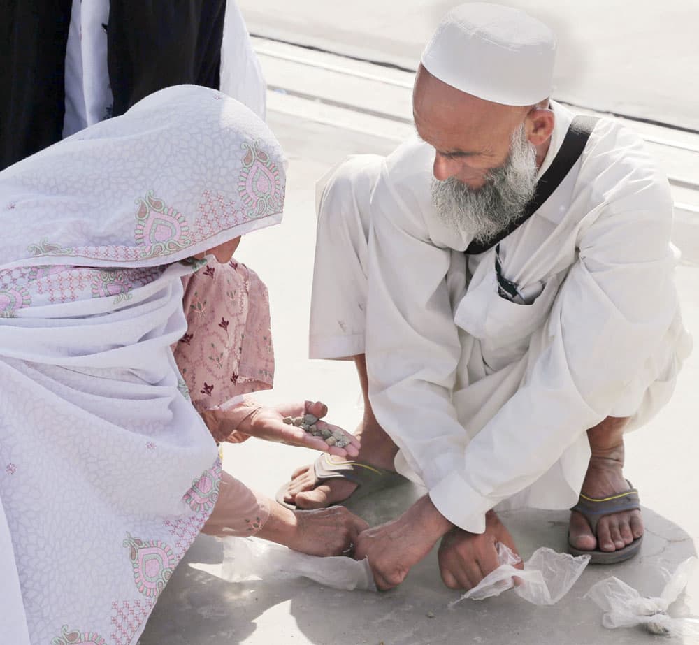 اثنان من الحجيج يعدان حصى الجمرات أمس.