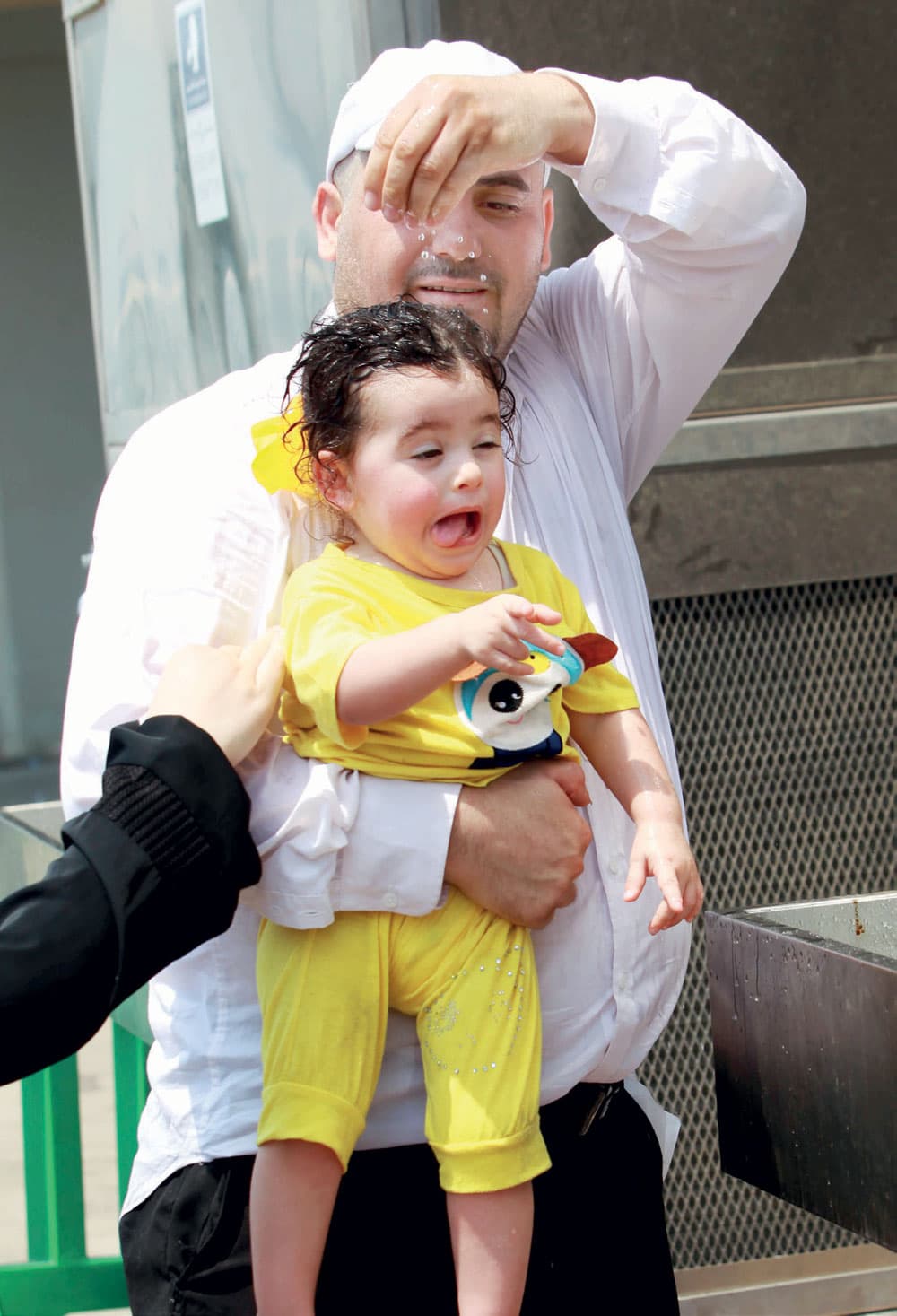 أب يحاول تخفيف درجة الحرارة عن ابنته في المشاعر المقدسة.