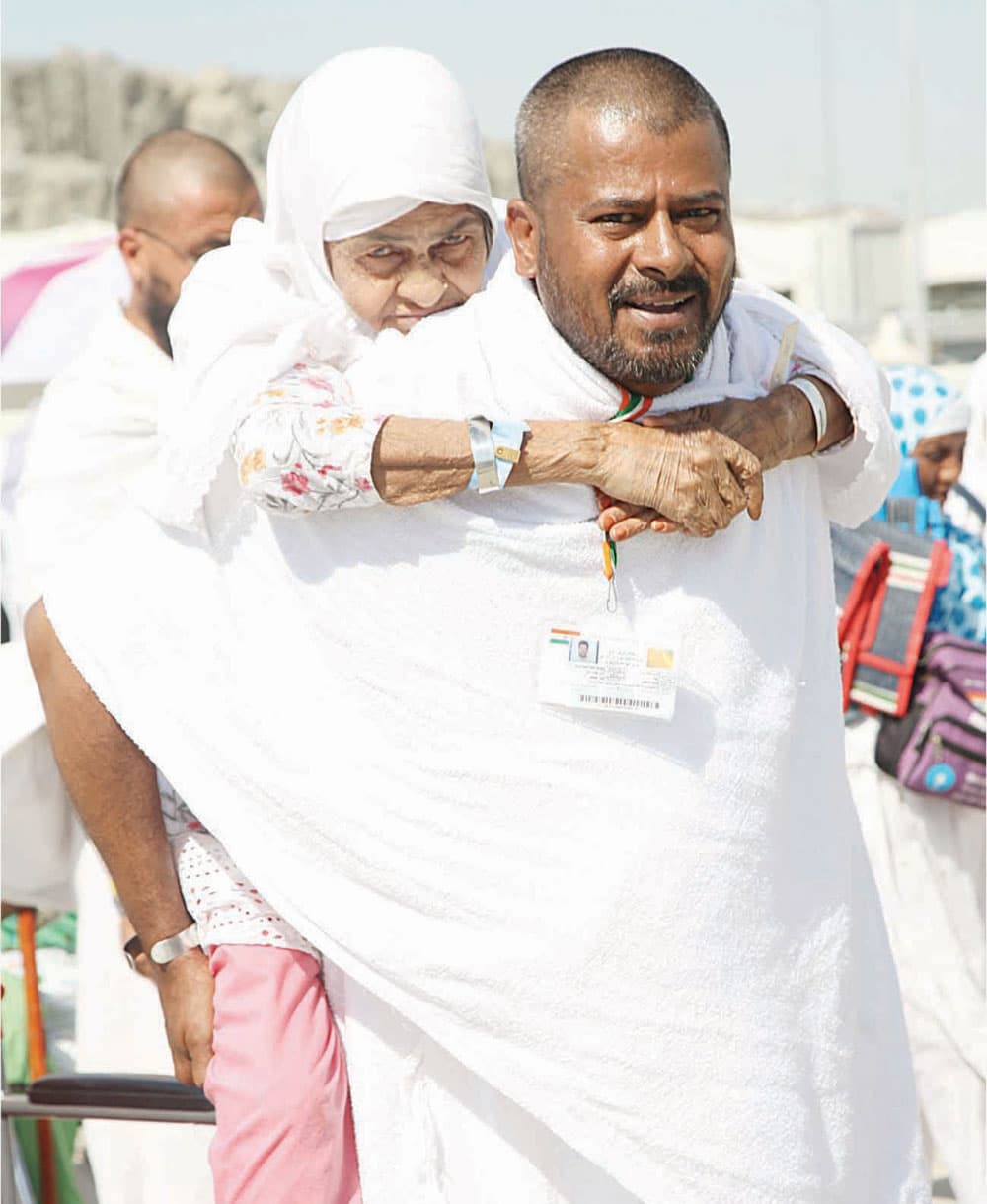 الحاج أنيس الهندي حاملا أمه خلال أداء المناسك.     تصوير: سلمان المرزوقي - "الاقتصادية"