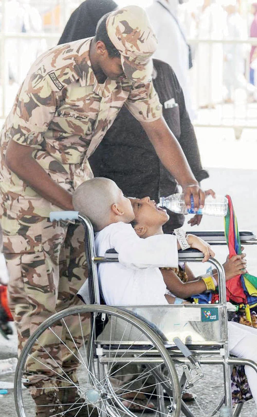  أحد رجال الأمن يسقي أحد أبناء ضيوف الرحمن.