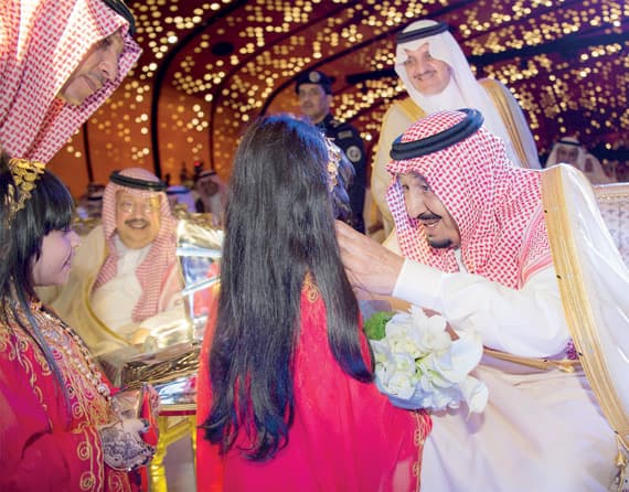 خادم الحرمين لدى تدشينه مركز الملك عبدالعزيز الثقافي العالمي، وتبدو طفلتان قدمتا حجر الإبداع للملك ووضعه في مجسم المركز.