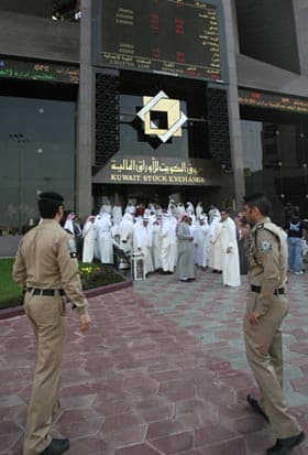 السوق المالية الكويتية في أعقاب الإغلاق بقرار من المحكمة الإدارية، ويبدو في الصورة رجلا أمن فيما يظهر في الخلفية أعداد من المتعا