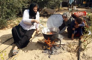 فلسطينية تطهو الطعام على الخشب بسبب نقص  الغاز في قطاع غزة  (رويترز)
