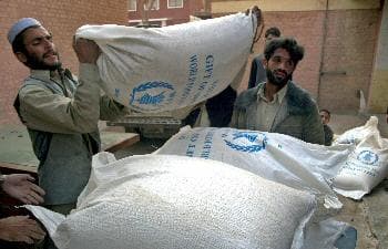 عمال يوزعون الحين على المتشردين الباكستانيين في مخيم بمنطقة (باجور) على الحدود مع أفغانستان (د ب أ)