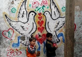 طفلان فلسطينيان من مخيم جباليا ولوحة الحب والسلام وراءهما (د ب أ)