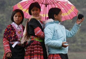 أطفال تحت المظلة في قرية هواتات على بعد (250كم) شمال غرب عاصمة فيتنام هانوي (رويترز)