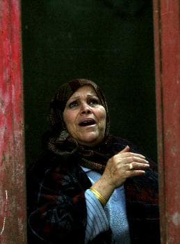 سيدة فلسطينية تنظر من بابا منزلها إلى آثار الدمار في غزة متوجعة على أبنائها و إخوانها و بلادها (د ب أ)