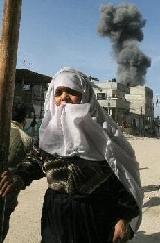 سيدة فلسطينية تحاول الابتعاد أثناء قصف جوي إسرائيلي على مخيم رفح في غزة (الفرنسية)