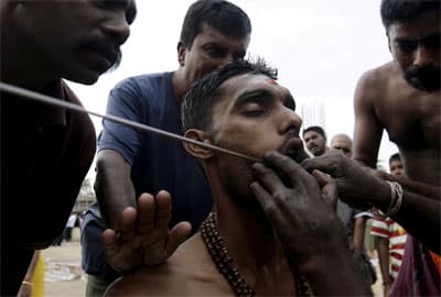 كاهن هندوسي يثقب فم أحد المتعبدين كطقوس خلال مهرجان "Thaipusam" في كوالالمبور.