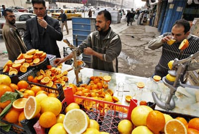 رجل عراقي يبيع عصير البرتقال في شارع تسوّق رئيسي في بغداد.