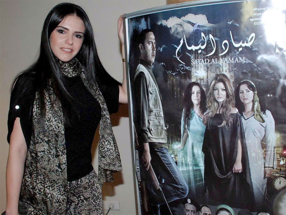 الممثلة المصرية دنيا أمام الملصق الترويجي لفيلمها السينمائي الجديد "صياد اليمام" في القاهرة.