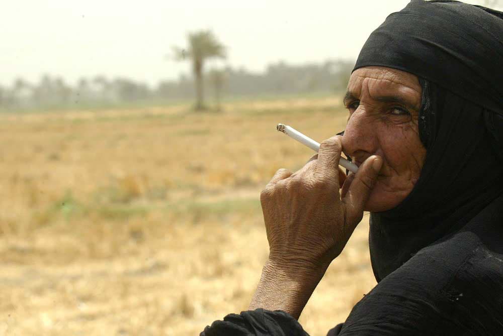 عجوز عراقية تنفث همومها مع دخان السجائر  في مدينة النجف