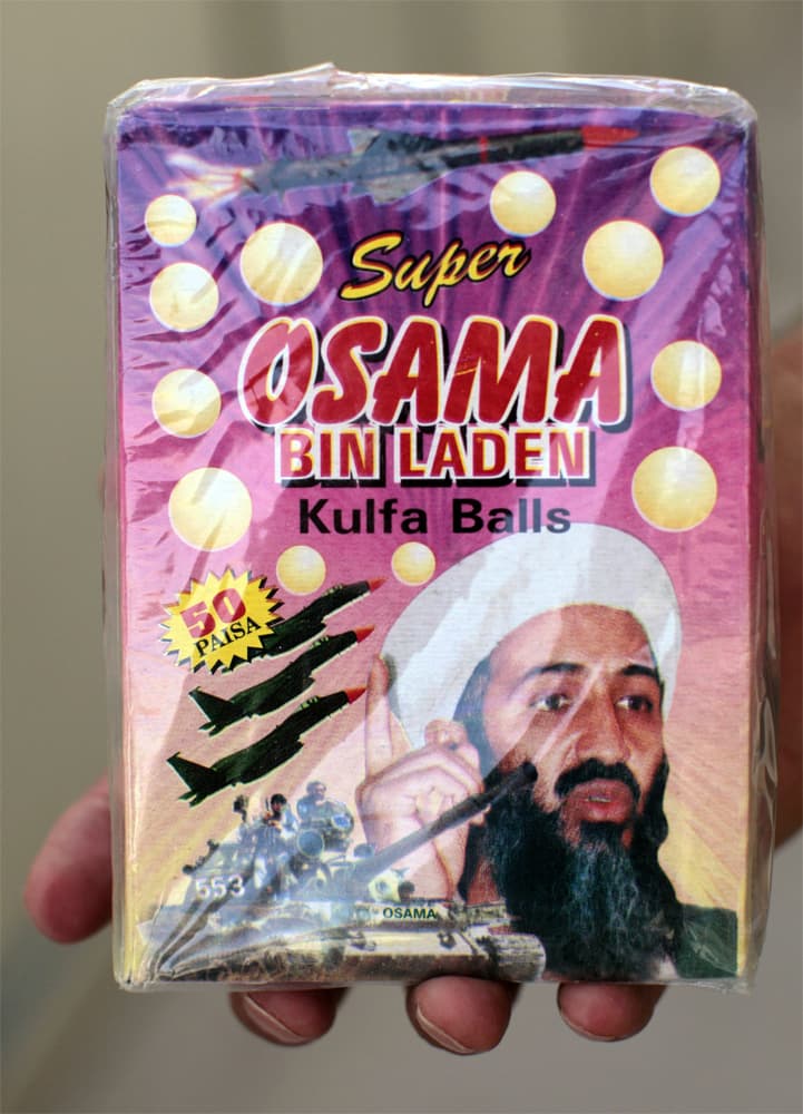رجل يحمل علبة حلويات باكستانية  بنكهة جوز الهند والحليب تحمل اسم "سوبر أسامة بن لادن - Super Osama Bin Laden, Kulfa Balls في سوق