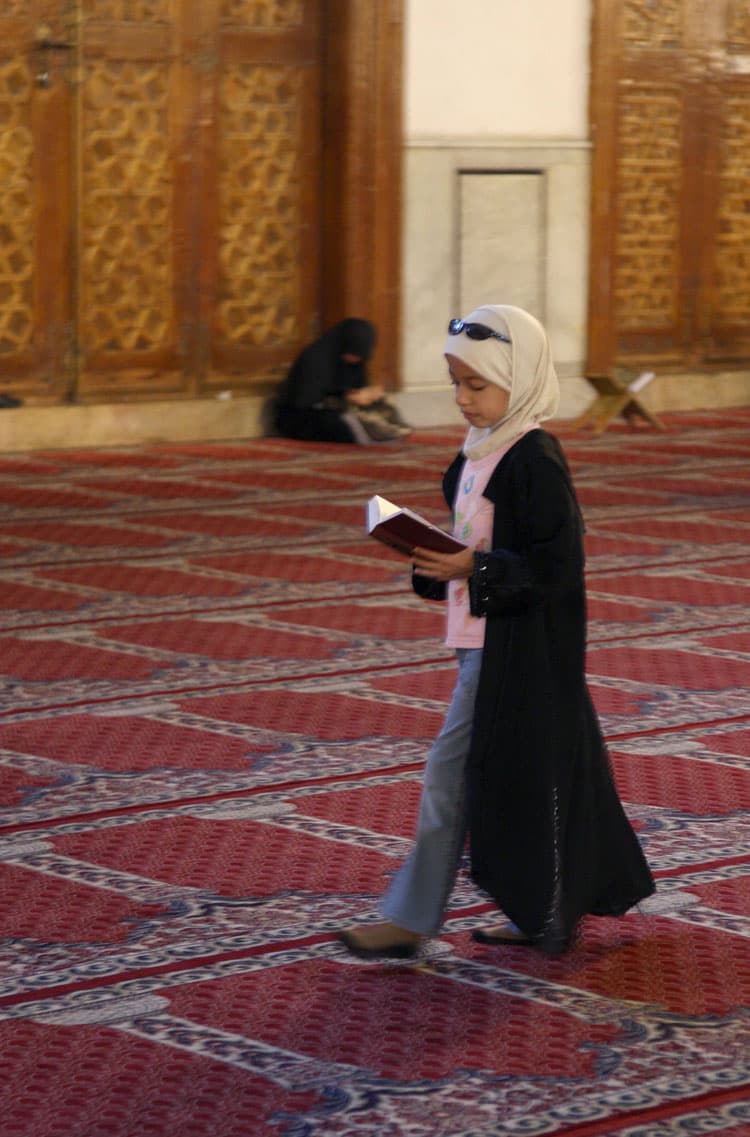 فتاة تقرأ القرآن الكريم وهي تمشي في جنبات المسجد الأموي المفعم بعبق التاريخ في العاصمة السورية دمشق.