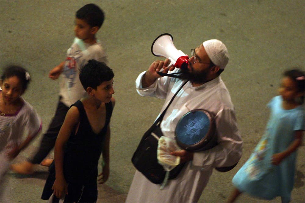 الحاج مسحراتي يجوب شوارع القاهرة لإيقاظ سكانها وتناول وجبة السحور.