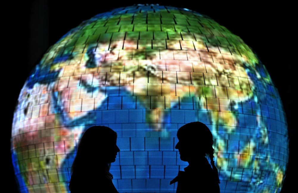 امرأتان في صورة أمام الكرة الأرضية المغطاة بآلاف المصابيح المنارة داخل "اكسبو 2010 العالمي للمعارض" الذي افتتح تحت شعار "مدينة أ