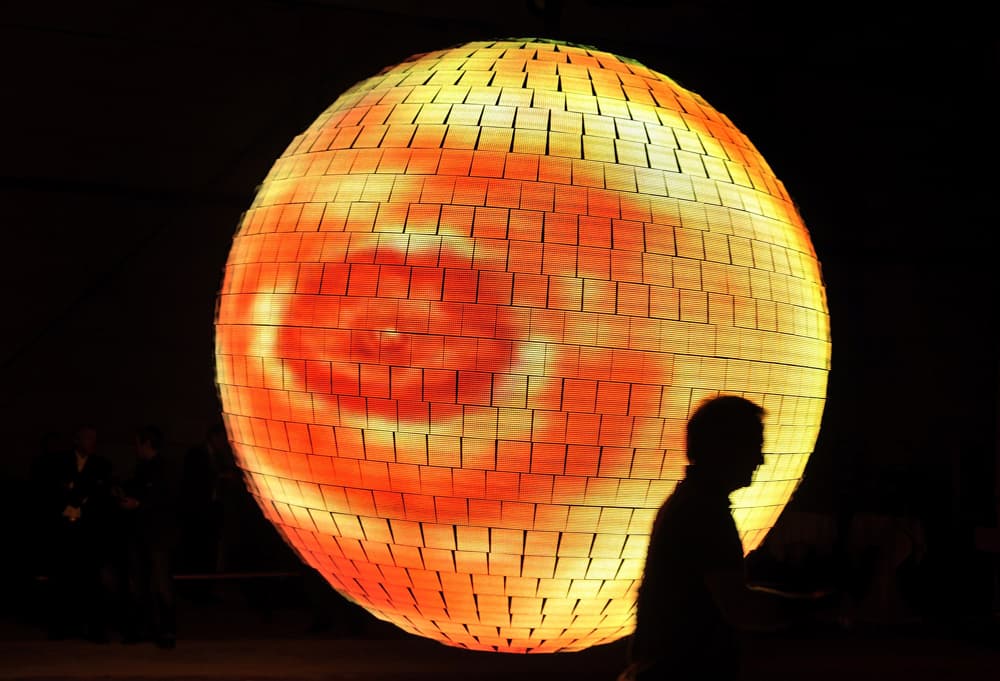 امرأتان في صورة أمام الكرة الأرضية المغطاة بآلاف المصابيح المنارة داخل "اكسبو 2010 العالمي للمعارض" الذي افتتح تحت شعار "مدينة أ