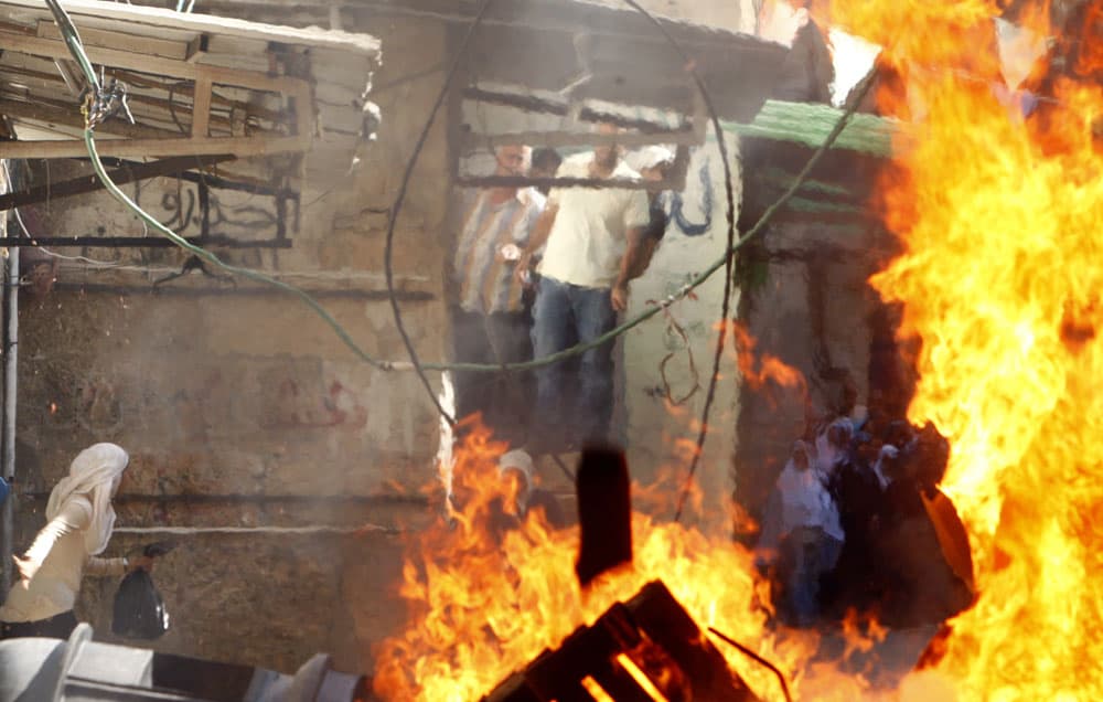 فلسطيني يحاول إخماد حريق بالقرب من أحد أبواب المؤدية إلى المسجد الأقصى حيث يواصل متطرفون يهود تعديهم السافر على أولى القبلتين.