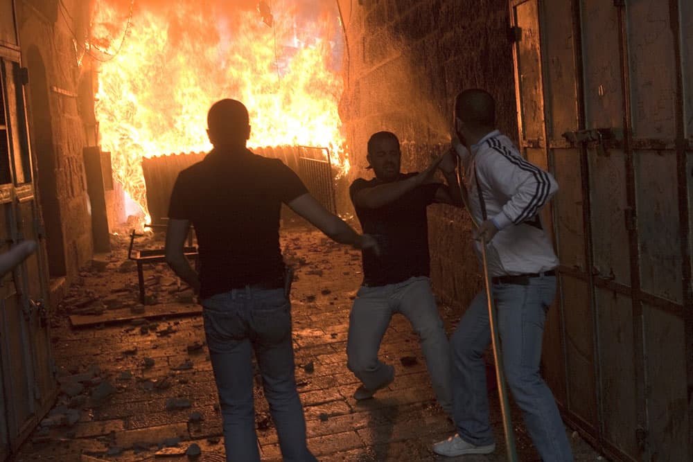 فلسطيني يحاول إخماد حريق بالقرب من أحد أبواب المؤدية إلى المسجد الأقصى حيث يواصل متطرفون يهود تعديهم السافر على أولى القبلتين.