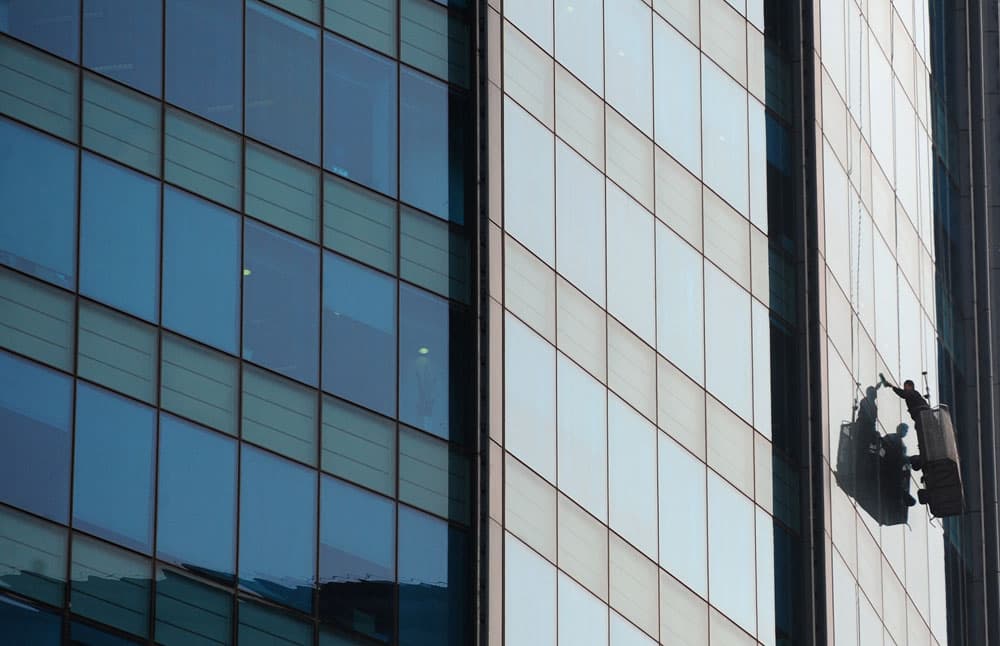 عامل يقوم بتنظيف نوافذ المكاتب من الخارج في إحدى ناطحات السحاب في العاصمة الصينية بكين