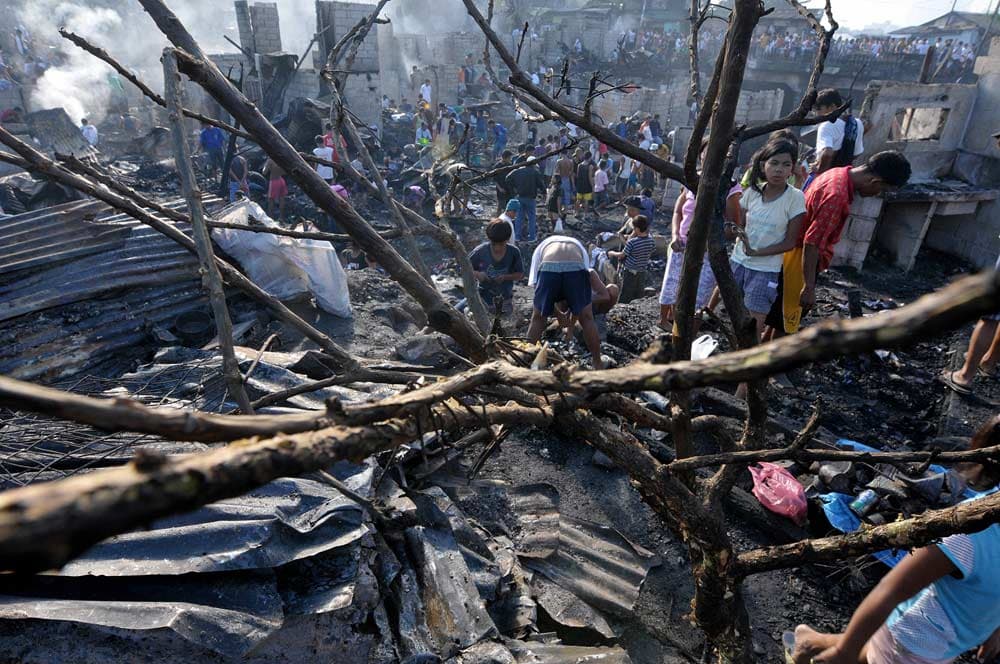 أطفال فلبينيين في حي فقير في مانيلا يبحثون عن حاجياتهم من تحت الأنقاض بعد أن أتت النيران على أكثر من 500 منزل في هذا الحي
