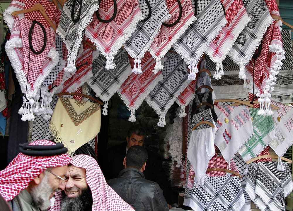 أردنيون يجربون أغطية الرأس الشعبية "الشماغ" التي يزدهر بيعها في الشتاء في متجر وسط العاصمة عمان.