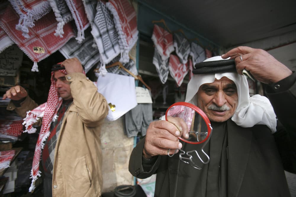 أردنيون يجربون أغطية الرأس الشعبية "الشماغ" التي يزدهر بيعها في الشتاء في متجر وسط العاصمة عمان.