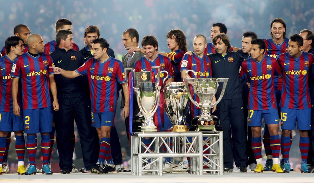 لاعبو نادي برشلونة الاسباني في لقطة جماعية  مع الكؤوس الست والتي تم حصدها خلال موسم 2009/2010  في كرة القدم.