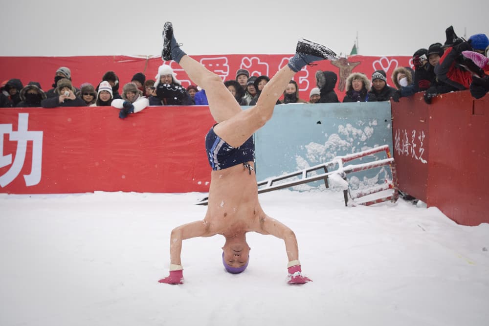 الصيني شياو يينغ73"  عاما" يقف على رأسه قبل أن يسبح في المياه المتجمدة في مدينة هاربين.