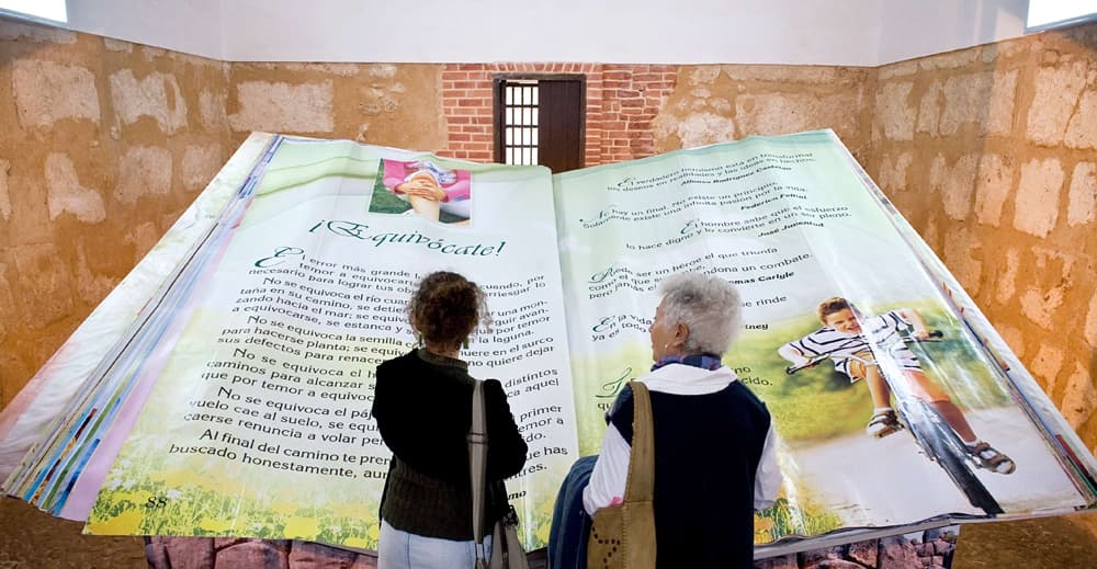 موظف كوبية في هافانا تقف بالقرب من أكبر كتاب في العالم وتحمل في يدها أصغر كتاب في العالم.