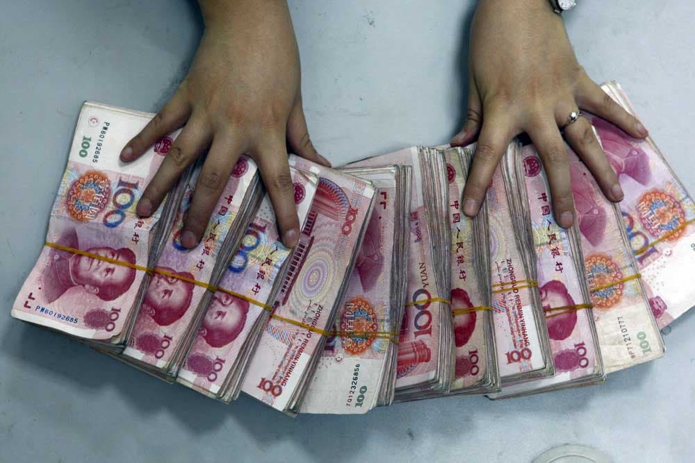 موظفة بنك ترتب حزمات من فئة 100 يولن في سوينينغ جنوب غرب الصين.