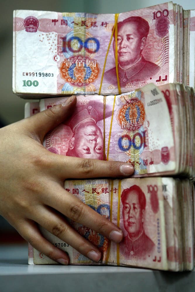 موظفة بنك ترتب حزمات من فئة 100 يولن في سوينينغ جنوب غرب الصين.