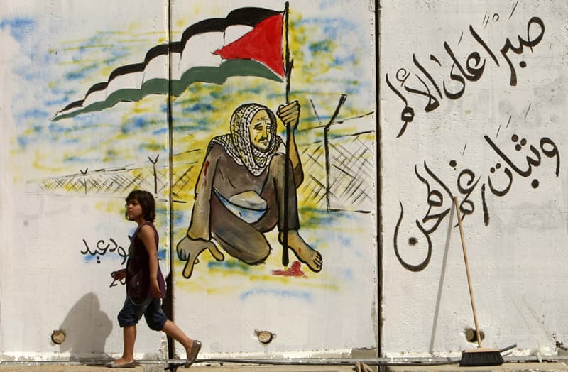 فتاة فلسطينية تمشي بالقرب من لوحة جدارية في معبر رفح الحدودي بعد أن قررت مصر إعادة فتح المعبر إلى أجل غير مسمى رد على الاعتداء ا