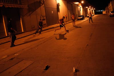شباب يلعبون كرة القدم في الشارع ليلاً في أسبانيا