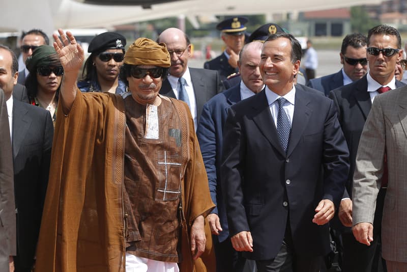 أحد أفراد الوفد المرافق للرئيس الليبي معمر القذافي يحمل ملابسه من الطائرة التي أقلتهم إلى روما للاحتفال السنوي الثاني بيوم الصدا