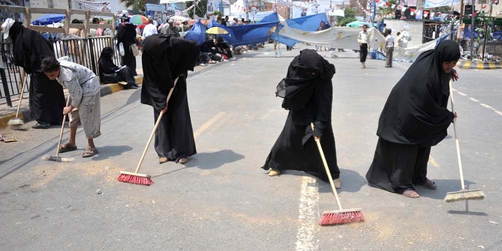 يمنيات ينظفن الشارع من الأوساخ بعد المظاهرة التي شهدتها مدينة صنعاء أمس