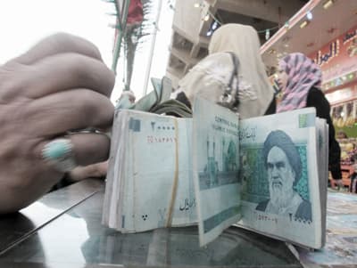 صراف يعد أوراقا نقدية من الريال الإيراني