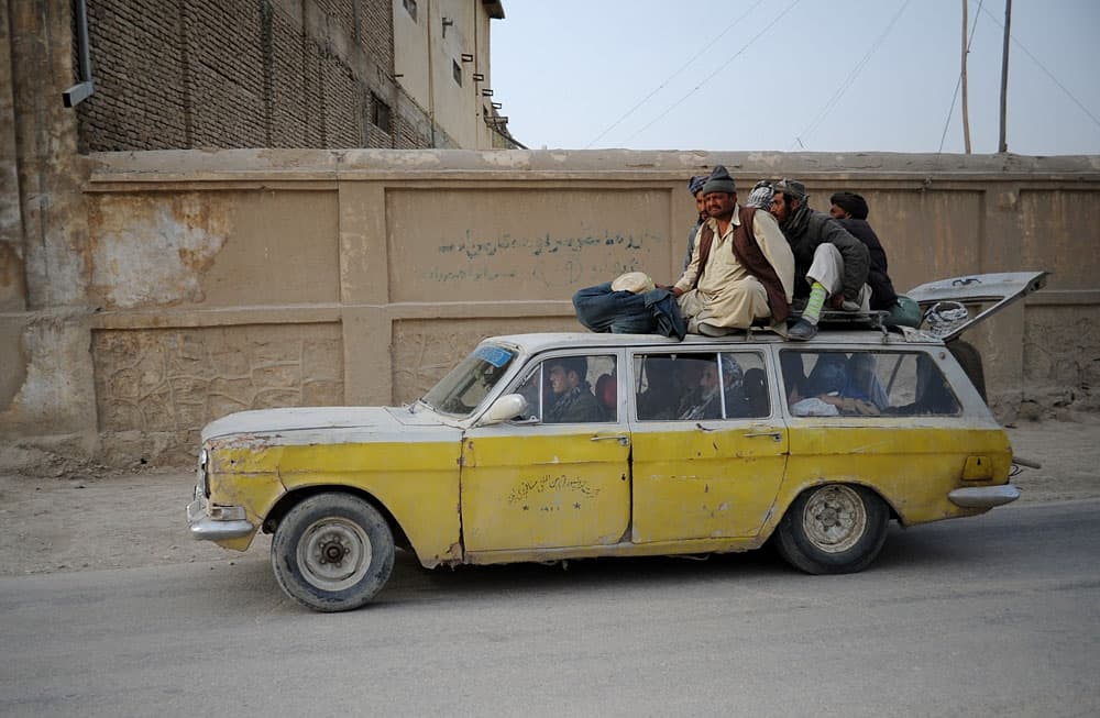 ركاب أفغان يجلسون على رأس سيارة أجرة في مزار الشريف