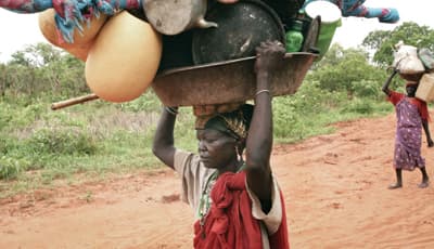 سودانية تحمل ما تمكنت من حمله من أوان منزلية