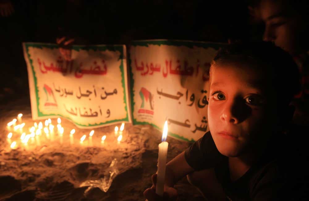 طفل فلسطيني يحمل شمعة خلال مظاهرة للتضامن مع الأطفال السوريين