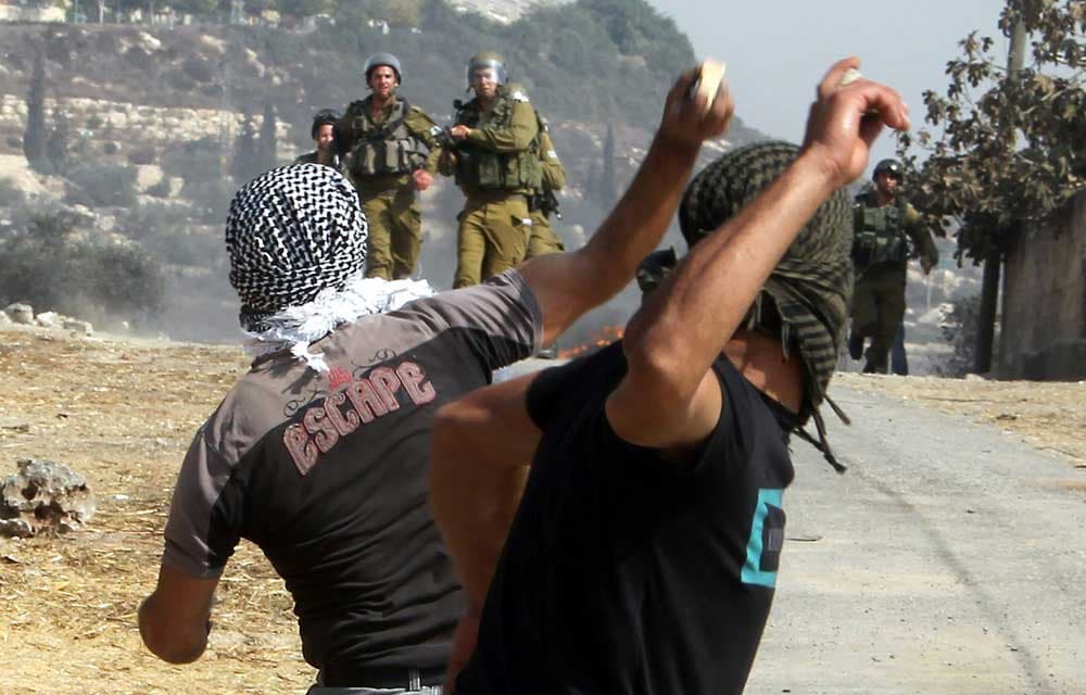 متظاهرون فلسطينيون يستعدون لرمي الحجارة باتجاه جنود اسرائيليين خلال مظاهرة في قرية كفر قدوم