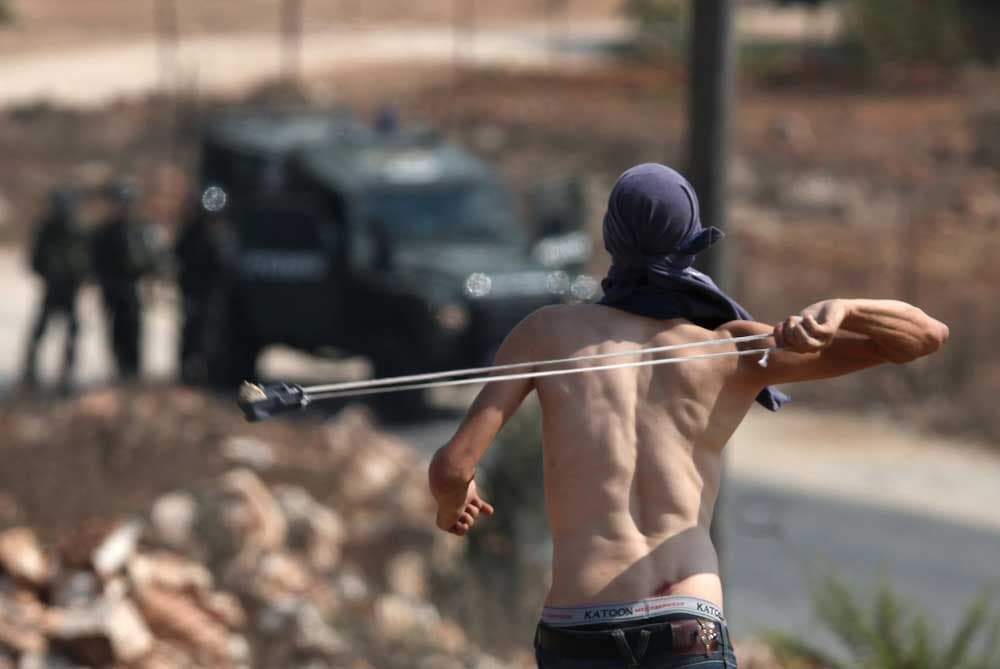 متظاهرون فلسطينيون يستعدون لرمي الحجارة باتجاه جنود اسرائيليين خلال مظاهرة في قرية كفر قدوم