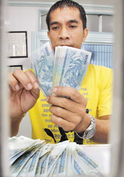 عامل يحسب أوراقا نقدية بالبيزو الفلبيني داخل محل صرافة في مانيلا