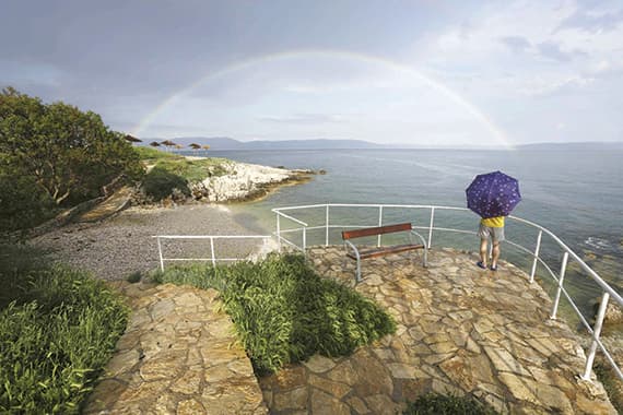 رجل يقف متأملاً قوس قزح في جزيرة كرواتية في البحر الأدرياتيكي أمس.