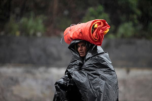 رجل تحت المطر يغطي نفسة بقطعة من البلاستيك في جامو في الهند