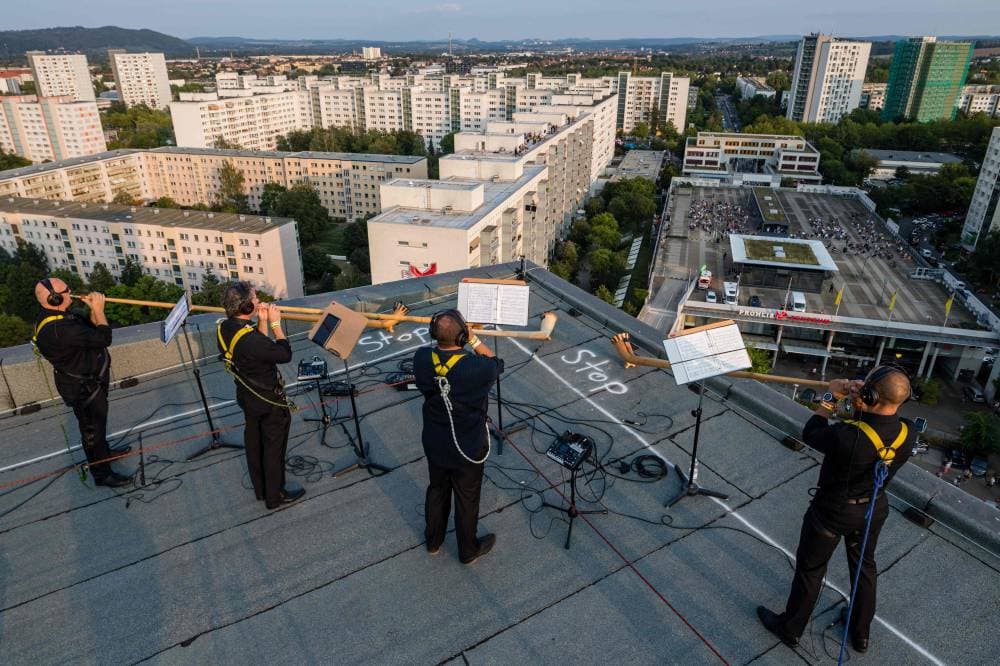 فرقة فنية تؤدي وصلة موسيقية على سطح مبنى شاهق شرق ألمانيا، بينما الجمهور على السطح المقابل، للحفاظ على التباعد الاجتماعي للحد من انتشار كورونا."الفرنسية"