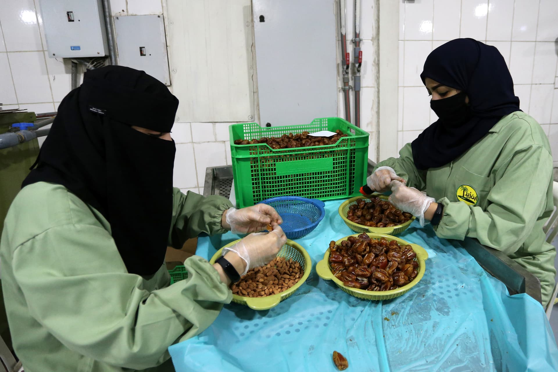 سعوديات يعملن على خط إنتاج مصنع لتعبئة التمور في الأحساء