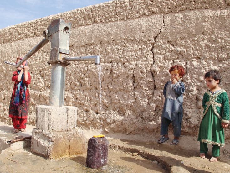 فتاة نازحة من المناطق المتضررة من الحرب في ولاية هلمند الأفغانية تشغل مضخة مياه في ملجأ مؤقت