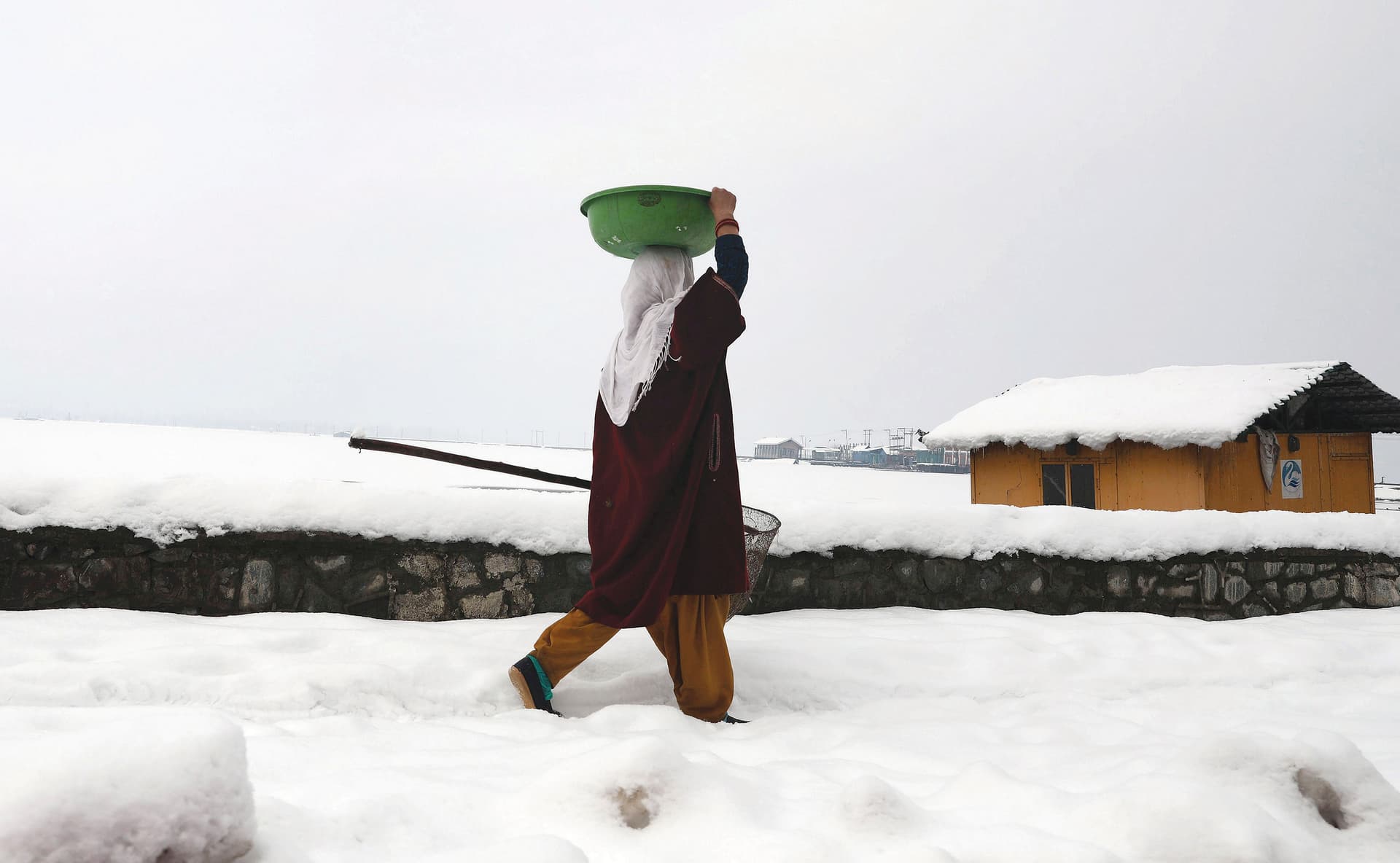 امرأة تمشي على ضفاف بحيرة دال المغطاة بالثلوج بعد تساقطها في مدينة سريناغار